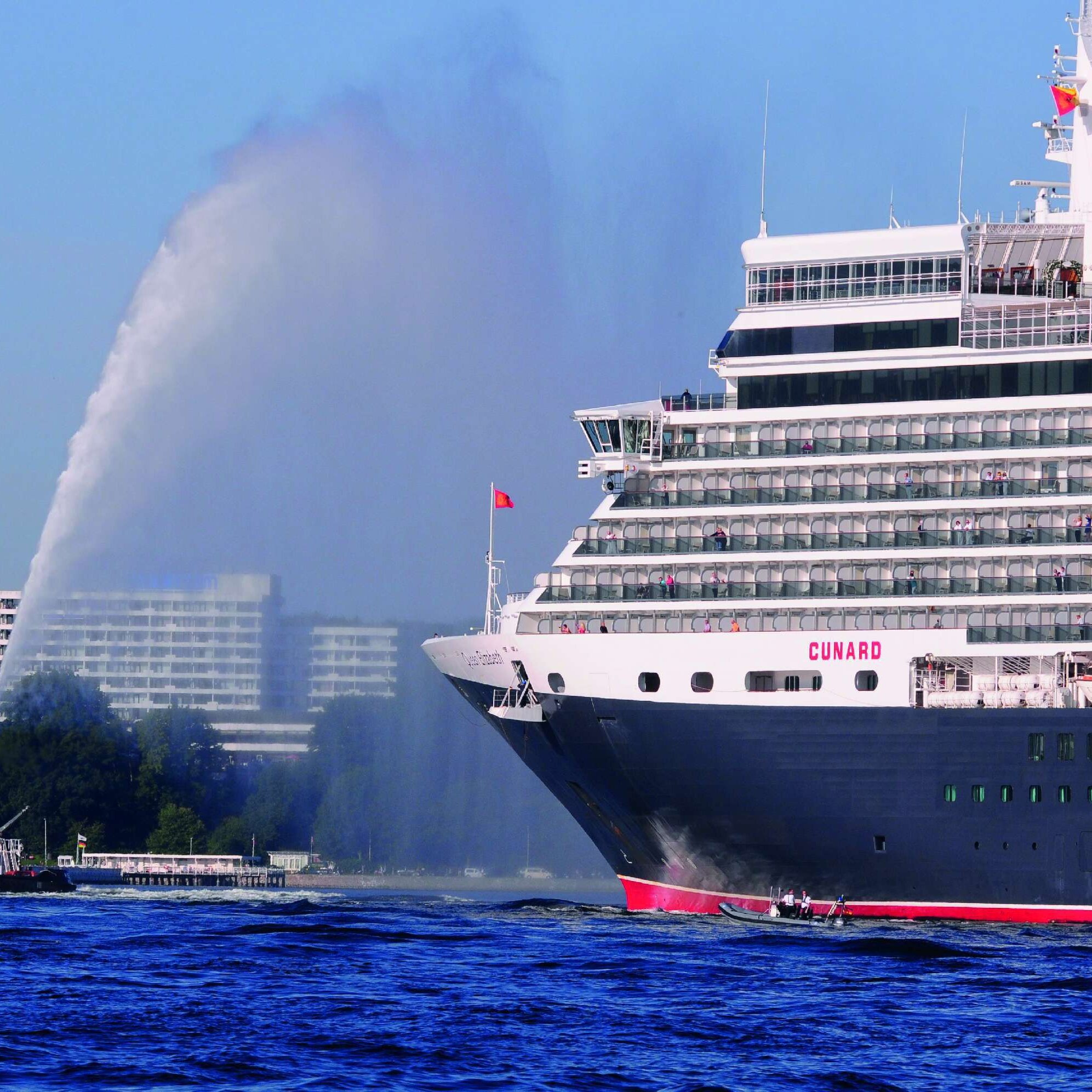 Vista esterna del Maritim Hotel Kiel, in primo piano la nave da crociera Queen Elizabeth e un rimorchiatore sull'acqua.
