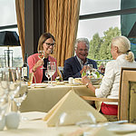 Happy guests enjoying a glass of wine and a meal at the restaurant of Maritim Hotel Dresden.