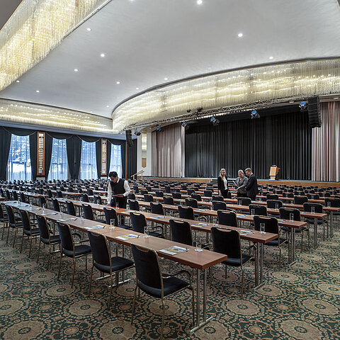 ala magnifica al Maritim Hotel Magdeburg con palco, sedie in fila e lussuoso lampadario.