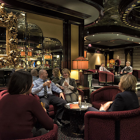 Ospiti che si rilassano al bar elegante del Maritim Hotel Bonn, godendo di drink in un'atmosfera piacevole.