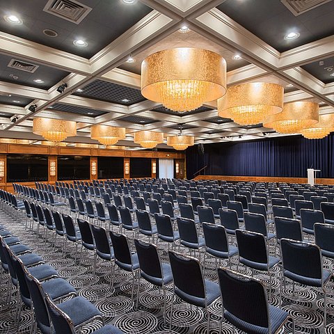 Salle élégante du Maritim Hotel Darmstadt avec sièges en rangée, lustres et équipement idéal pour les événements.