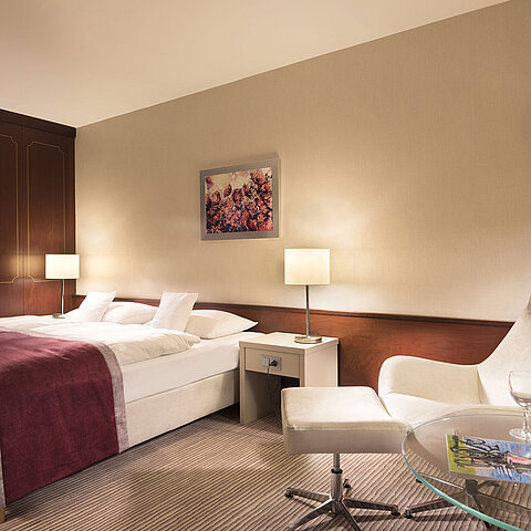 Camera classica al Maritim Hotel Bonn, arredata con letto matrimoniale, poltrona, tavolo e illuminazione moderna.