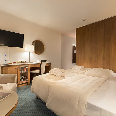 Chambre classique au Maritim Seehotel Timmendorfer Strand avec lits jumeaux, minibar, bureau, TV et coin salon.