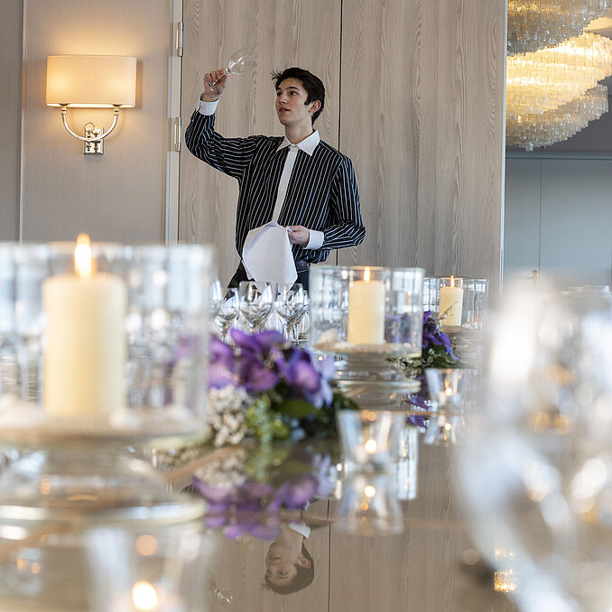 Les collaborateurs du salon Oslo de l'hôtel Maritim de Kiel vérifient un verre de vin, une table festive avec des bougies et des décorations florales.