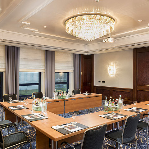 Salon Rheinaue de l'hôtel Maritim Bonn, préparé pour une conférence en U, équipé de boissons et de fournitures.