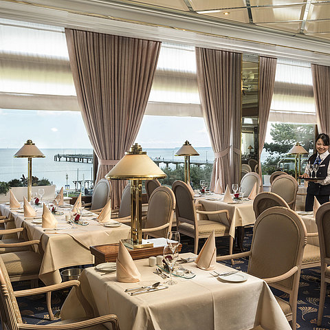 Ristorante elegante con vista mare e tavoli apparecchiati al Maritim Seehotel Timmendorfer Strand.