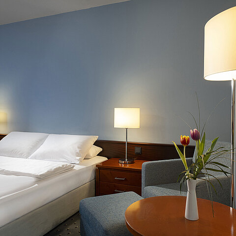 Camera singola confortevole con letto queen-size, mobili moderni e luce ambientale al Maritim Hotel Darmstadt.