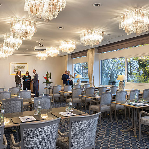 Le salon Copenhague de l'hôtel Maritim de Kiel, une élégante salle de conférence avec des lustres, des tables nappées et de grandes fenêtres.
