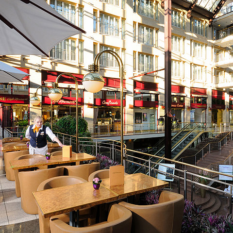 Café Heumarkt presso l'Hotel Maritim Colonia con posti a sedere e personale di servizio in un'atmosfera elegante.