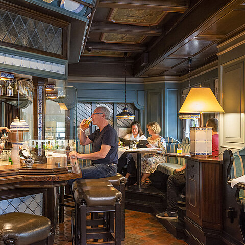 Accogliente bar dell'hotel in stile tradizionale con ospiti che gustano drink e un barista che serve birra.