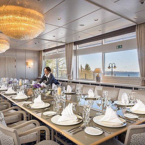 Salon Oslo à l'hôtel Maritim de Kiel, longue table festive avec vue sur la mer, chandeliers, le personnel oriente la pièce.