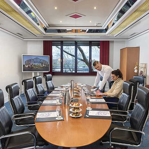 Deux personnes travaillant dans le Salon Boardroom avec des ordinateurs portables et des boissons sur la table.