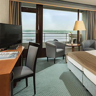 Chambre supérieure au Maritim Hotel Kiel avec bureau, coin salon, grand lit double et balcon avec vue sur le fjord.