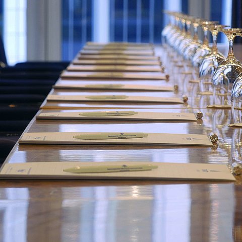 Gros plan d'une table de conférence préparée à l'hôtel Maritim proArte Berlin, avec des carnets et des verres à vin.