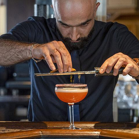 Barman che rifinisce un cocktail al bar del Maritim Hotel Würzburg.