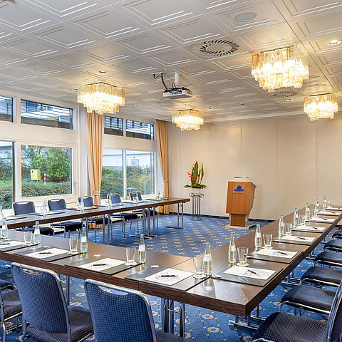 Le salon Lübeck de l'hôtel Maritim de Kiel, une salle de conférence moderne avec des sièges en forme de U, de grandes fenêtres et des lustres.