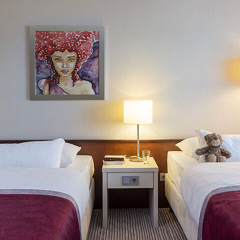 Camera familiare classica al Maritim Hotel Bonn con due letti, comodino e arte moderna per un soggiorno confortevole.