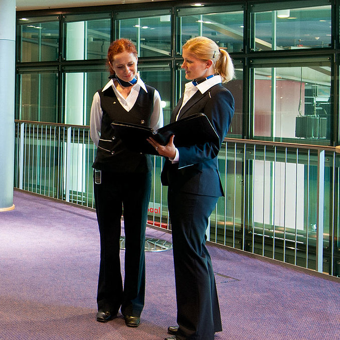 Foyer de l'hôtel Maritim de Dresde avec deux employés en uniforme, des tables hautes et un buffet de fruits.