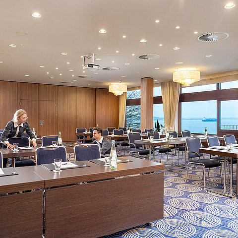 Salle Kiel à l'hôtel Maritim de Kiel, grande salle de conférence avec vue sur la mer, un personnel aimable installe les tables.