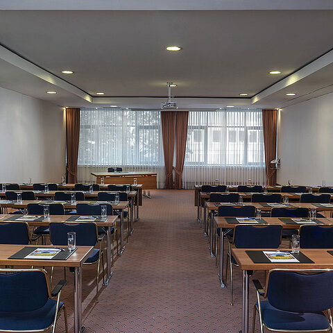 Sala riunioni moderna al Maritim Hotel Magdeburg con sedie in fila, luce naturale e attrezzature tecniche.