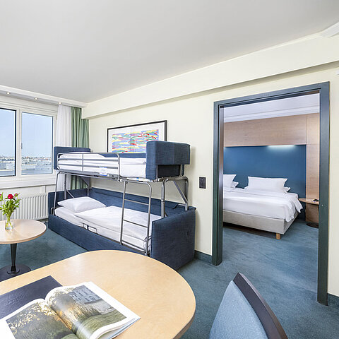 Moderna suite familiare del Maritim proArte Hotel Berlin con letto a castello, area salotto e camera da letto separata.