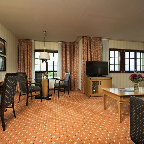 Junior Suite al Maritim Hotel Dresden con area salotto elegante, grande scrivania e design moderno.