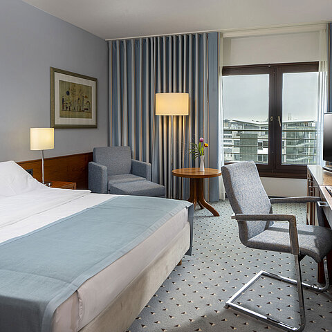 Camera doppia comfort al Maritim Hotel Darmstadt con area salotto accogliente, scrivania moderna e vista sulla città.